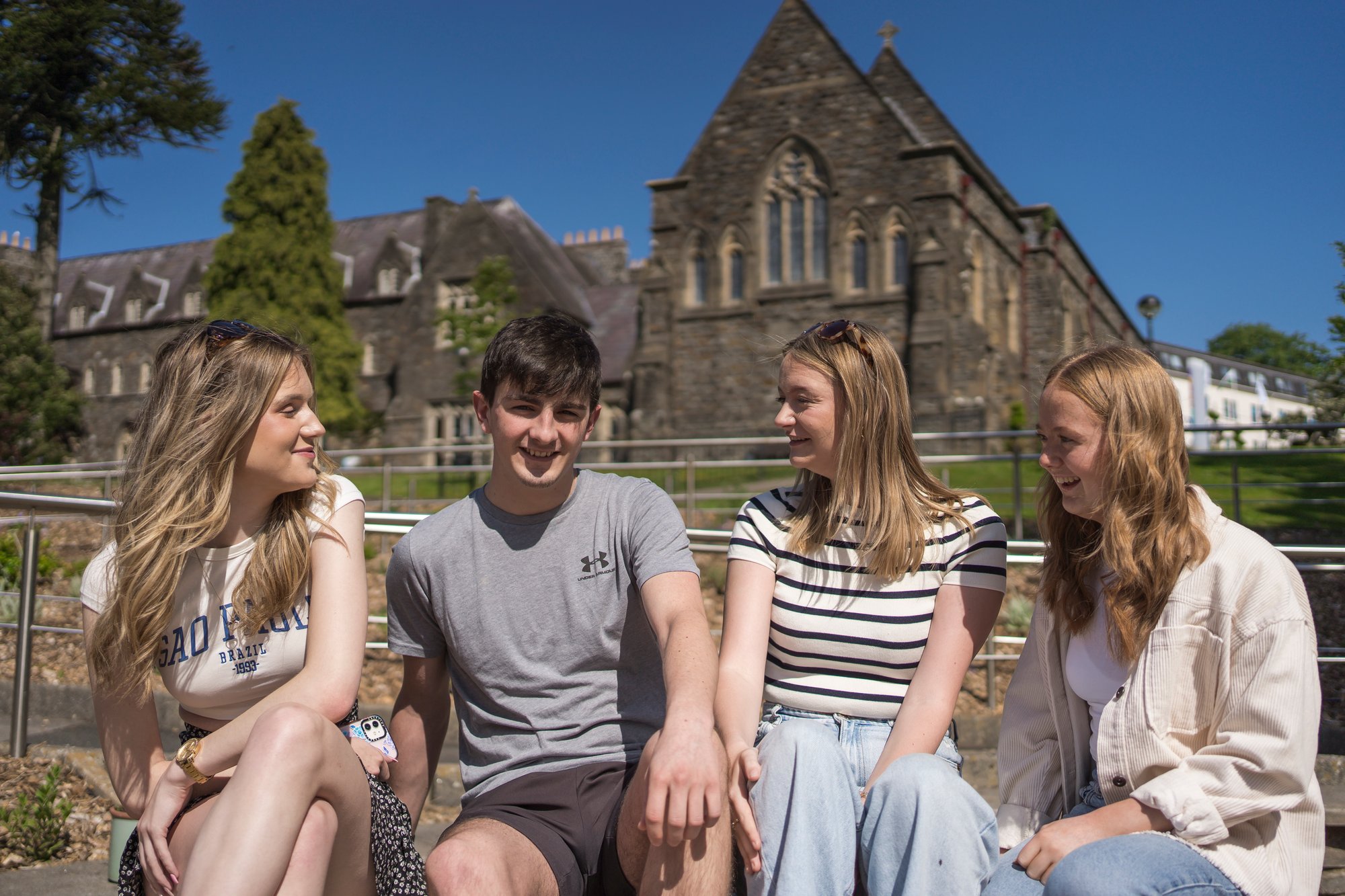 four students outside with carmarthen campus backdrop four students outside with carmarthen campus backdrop